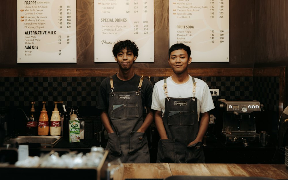 Two baristas smiling behind a cafe counter